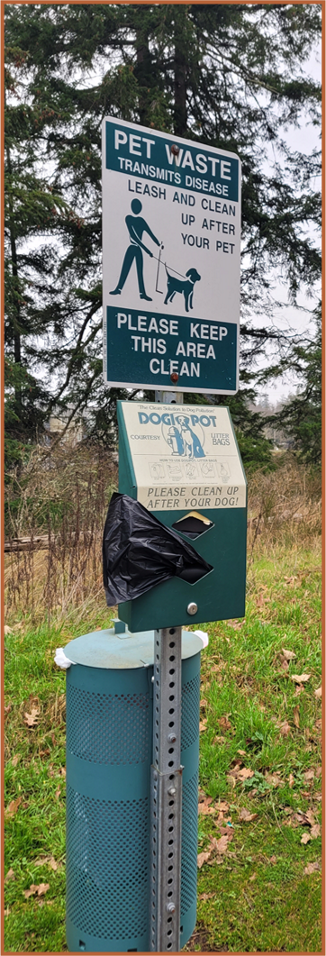 Picture of a pet waste station in DuPont, WA with a post and sign, a garbage can, and pet waste bags